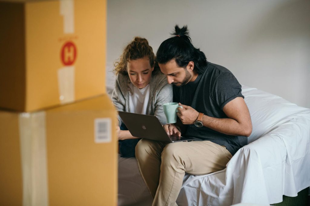 Couple checking status updates on laptop while moving into new Toronto home