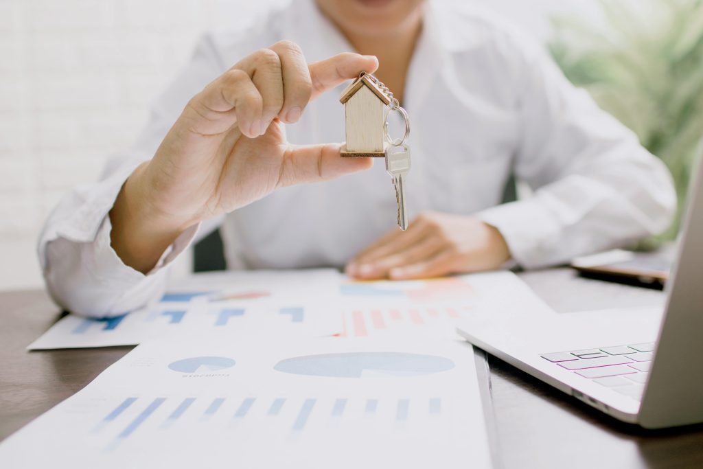 Real estate agent holding house keychain over business reports in Toronto